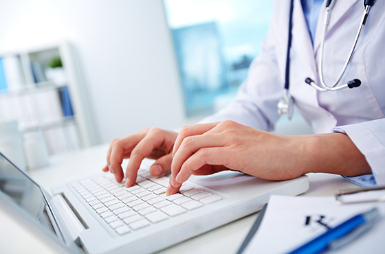 A medical professional typing on a laptop computer