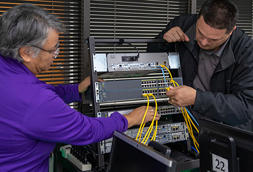 Information Technology student and instructor reviewing the interior of a computer