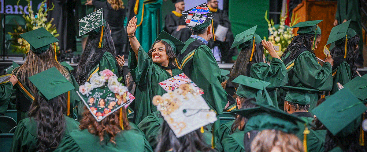 Midland College student waving to family and friends during graduation ceremony