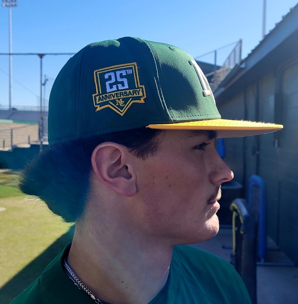smc baseball player showing of 25th anniversary cap
