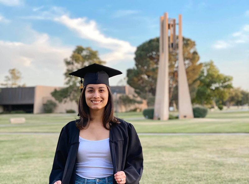 The image to use for this article. Listing image managed through RSS tab. Adrianna Chavez in her graduation regalia in front of Hodge Carillon on the MC campus.