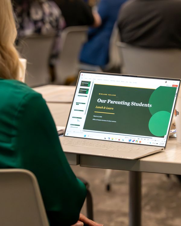 slunch and learn attendee sits at a table with her laptop looking at a screen that says support for parenting students