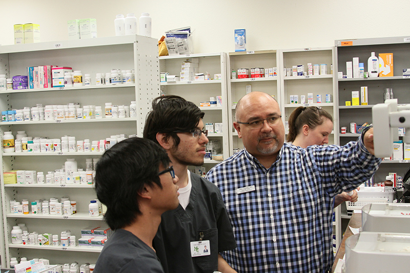 sPharmacist Julio Castillo (far right) explains procedure to Students Khait Sarapao (left) and and Jeremiah Salcido (center) at Graham’s Pharmacy on Wall Street in Midland.