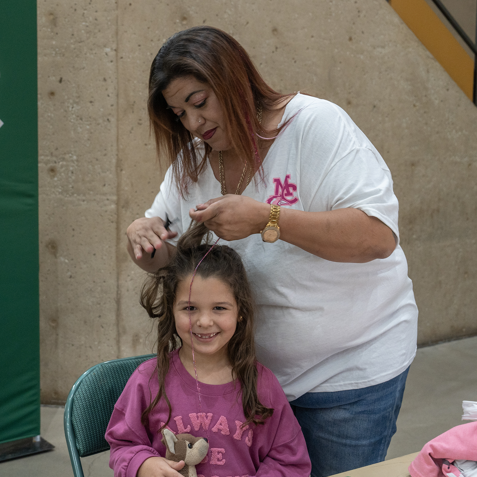 The image to use for this article. Listing image managed through RSS tab. MC cosmetology student puts a pink hair extension in a young girl's hair 