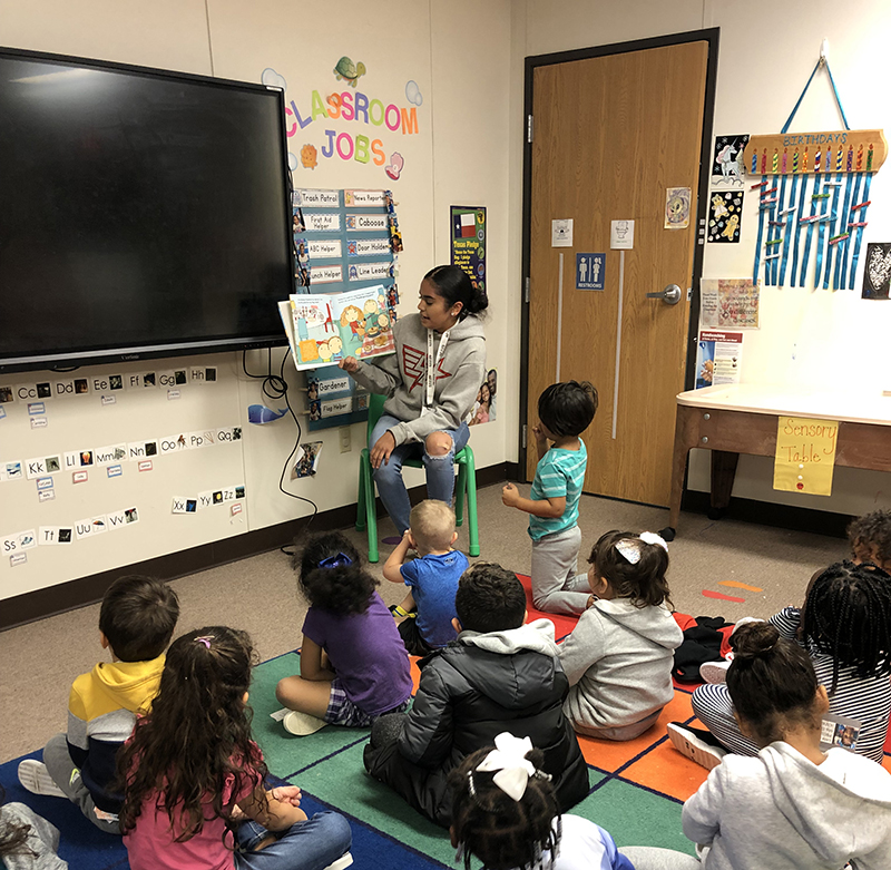 The image to use for this article. Listing image managed through RSS tab. MC AAT student reading to pre-k academy students.
