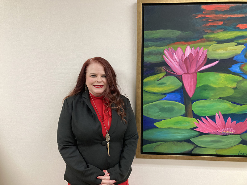 The image to use for this article. Listing image managed through RSS tab. Michelle Roys standing in front of picture of flower.