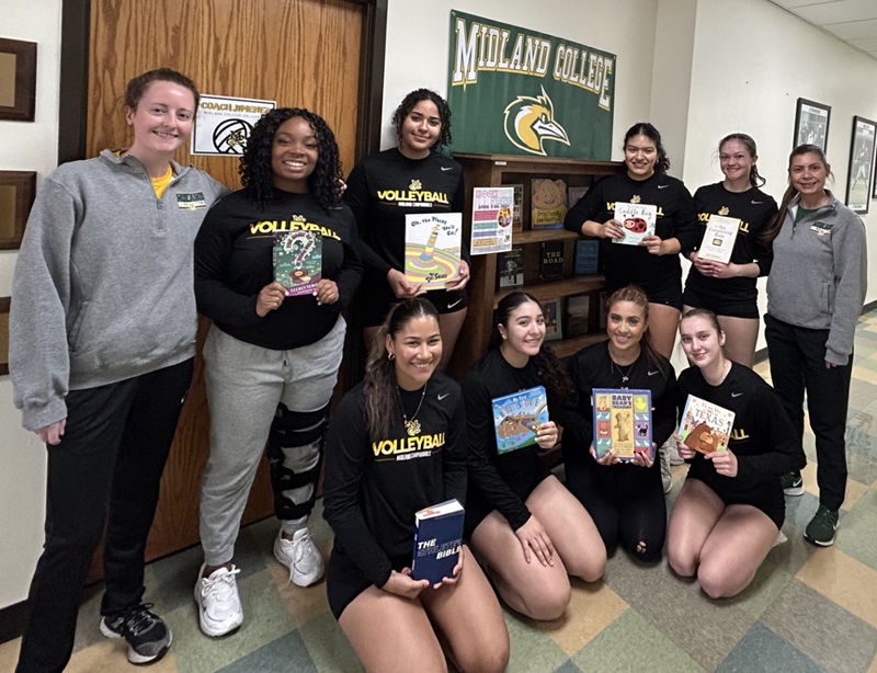 sMidland College volleyball players pose near book drive drop-off location.