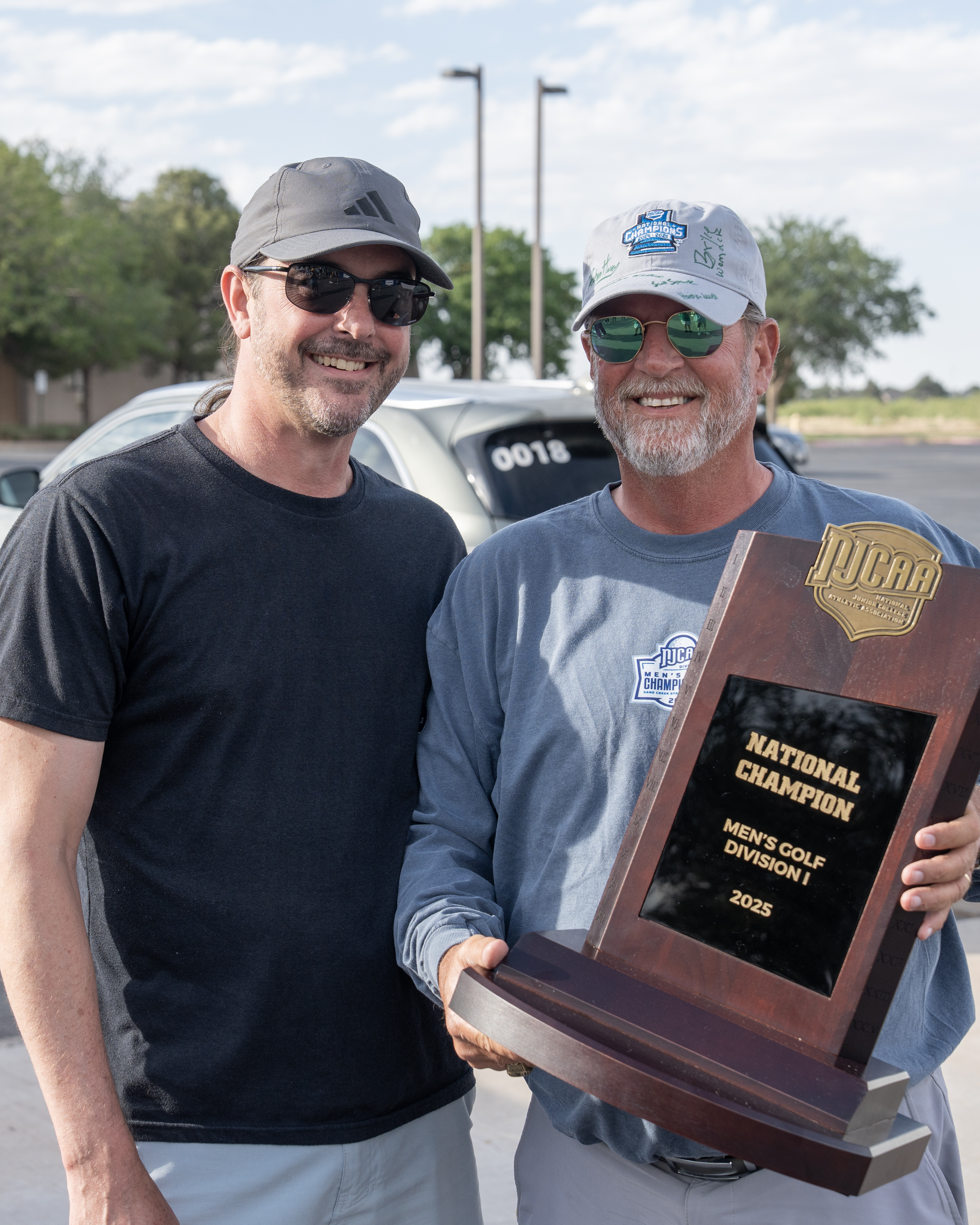 smc president dr. damon kennedy and mc golf coach walt williams pose with national trophy
