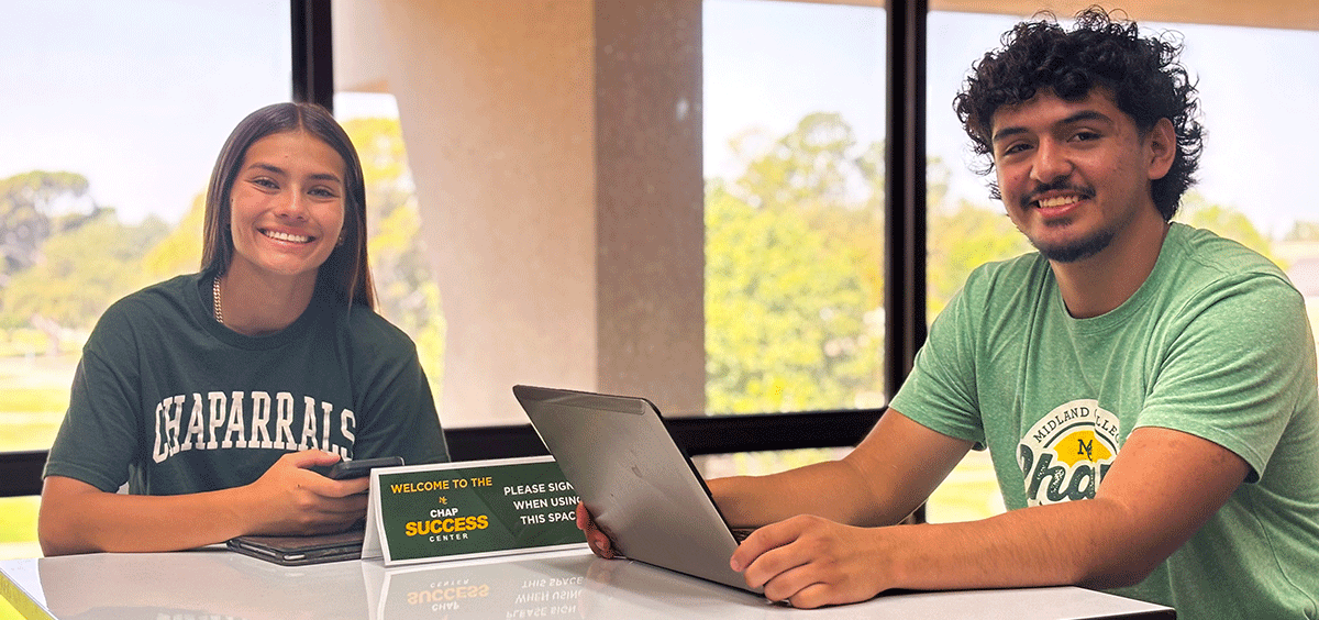 Two Midland College students smiling at the camera while working in the Chap Success Center